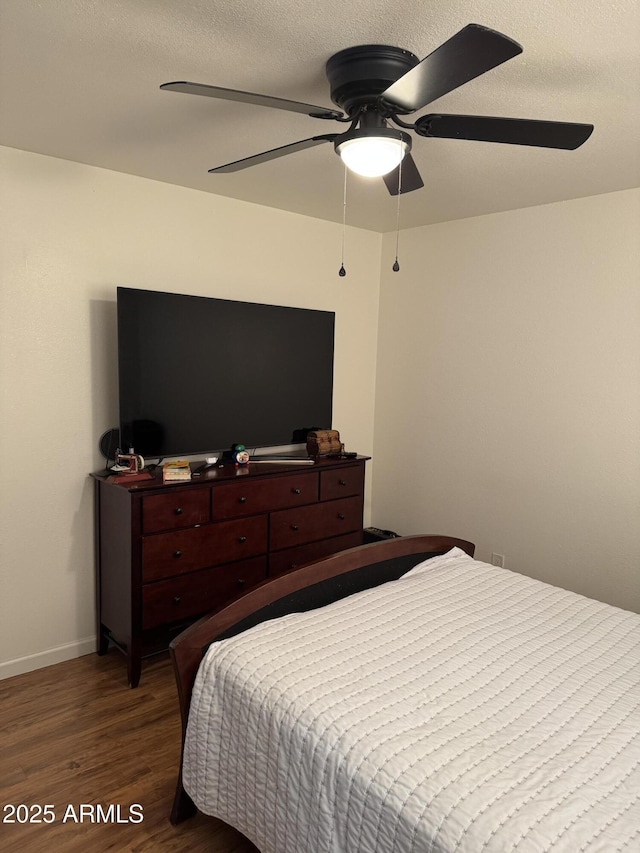 bedroom featuring baseboards, wood finished floors, and ceiling fan