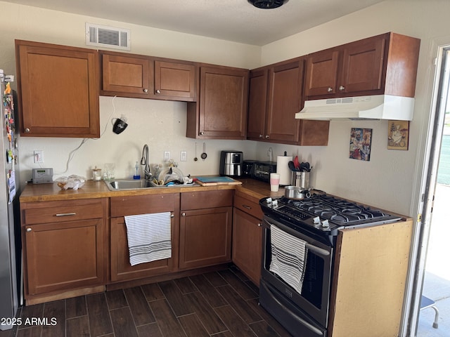 kitchen with a sink, visible vents, stainless steel appliances, under cabinet range hood, and dark wood finished floors