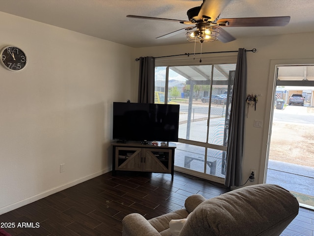 living area with a ceiling fan, dark wood finished floors, and baseboards