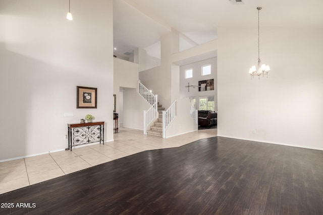 6971 W El Cortez Pl, Peoria, AZ 85383 - unfurnished living room featuring light wood finished floors, high vaulted ceiling, a chandelier, stairs, and baseboards