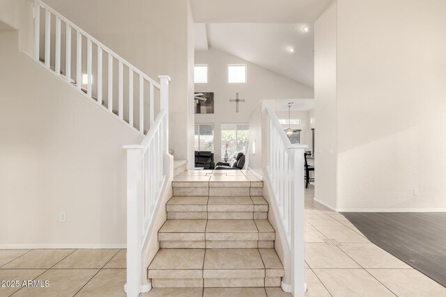 6971 W El Cortez Pl, Peoria, AZ 85383 - staircase featuring tile patterned floors, high vaulted ceiling, and baseboards