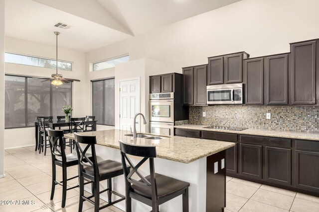 6971 W El Cortez Pl, Peoria, AZ 85383 - kitchen featuring a sink, appliances with stainless steel finishes, light tile patterned floors, tasteful backsplash, and high vaulted ceiling