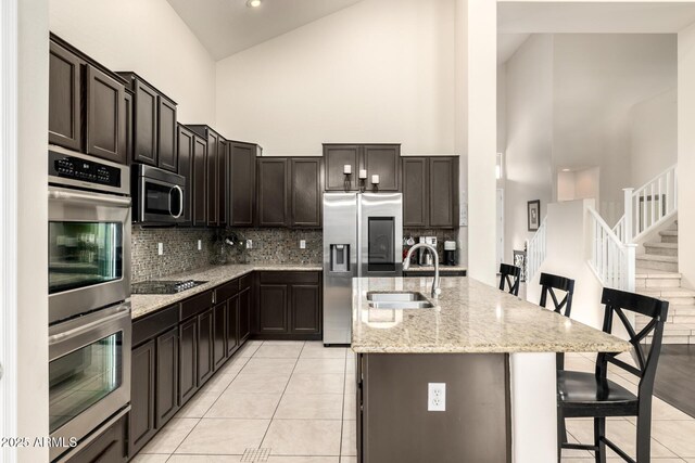 6971 W El Cortez Pl, Peoria, AZ 85383 - kitchen featuring high vaulted ceiling, appliances with stainless steel finishes, a sink, tasteful backsplash, and an island with sink