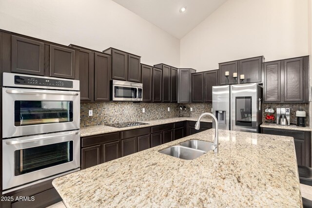 6971 W El Cortez Pl, Peoria, AZ 85383 - kitchen featuring stainless steel appliances, a sink, backsplash, dark brown cabinetry, and high vaulted ceiling