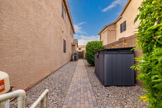 6971 W El Cortez Pl, Peoria, AZ 85383 - view of side of home with stucco siding, cooling unit, and a gate
