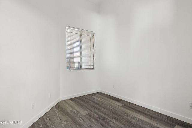 spare room with dark wood-type flooring and baseboards