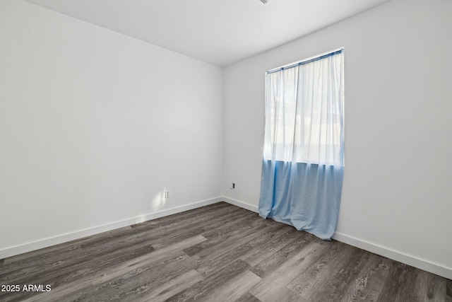 empty room featuring baseboards and dark wood-style floors