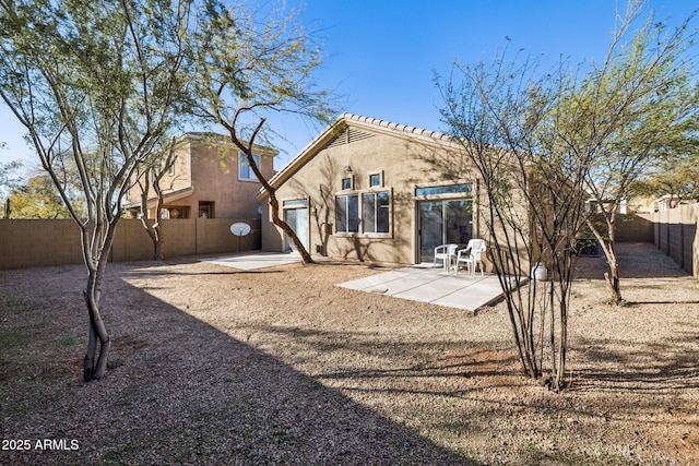 rear view of house featuring a fenced backyard, a patio, and stucco siding