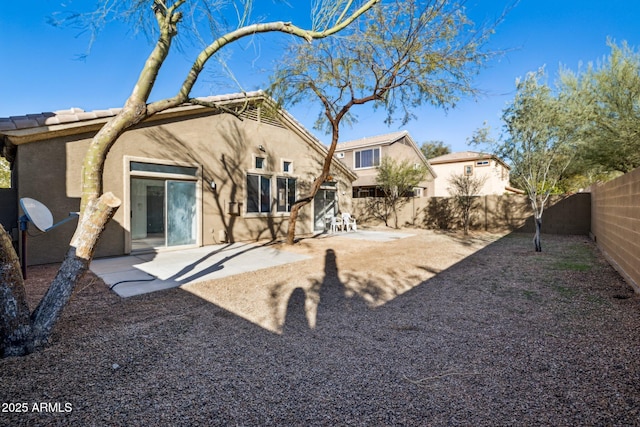 rear view of property featuring a patio, a fenced backyard, and stucco siding