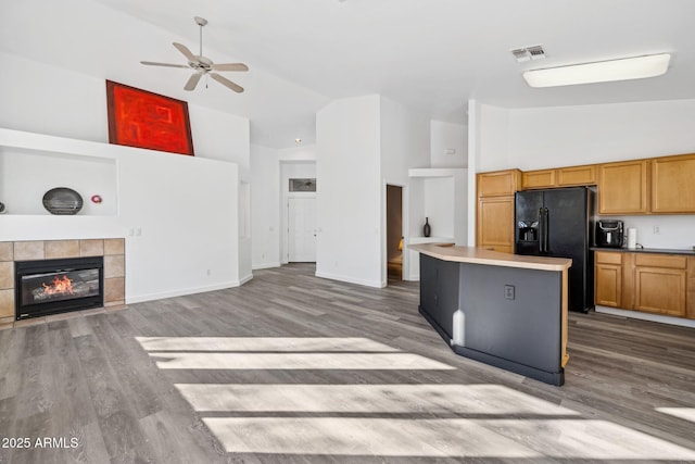 kitchen with a ceiling fan, visible vents, black refrigerator with ice dispenser, wood finished floors, and open floor plan
