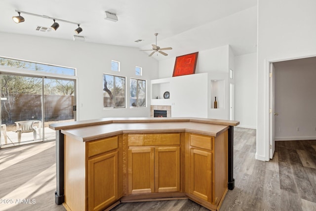 kitchen with a tiled fireplace, light wood finished floors, visible vents, and ceiling fan