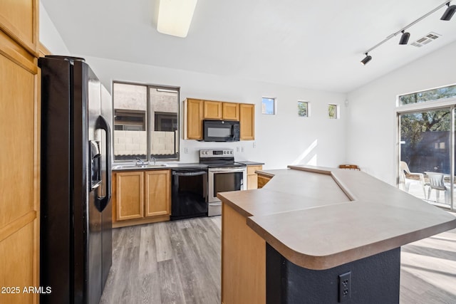 kitchen with rail lighting, light wood-style flooring, a center island, lofted ceiling, and black appliances