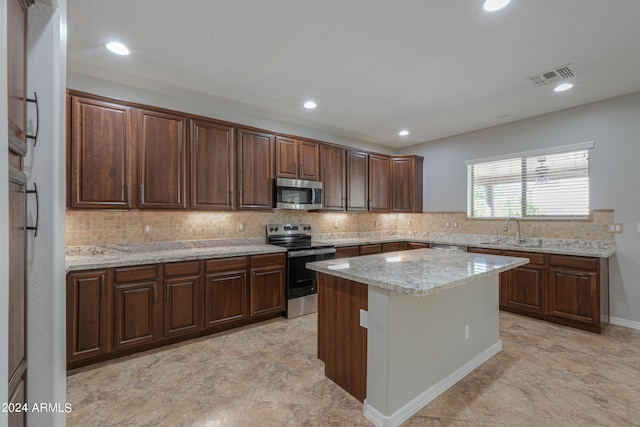 kitchen with light stone countertops, a center island, tasteful backsplash, sink, and appliances with stainless steel finishes