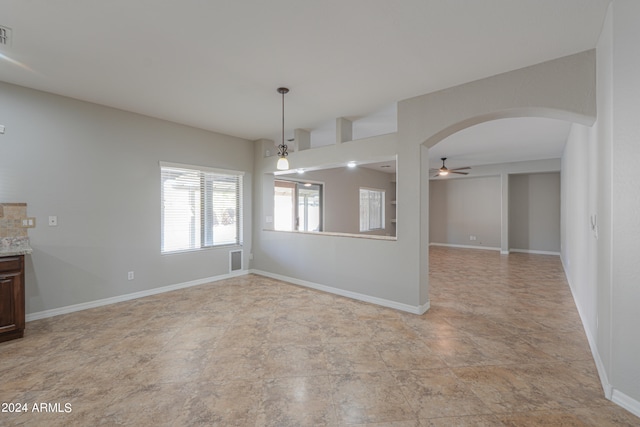 unfurnished dining area with ceiling fan with notable chandelier