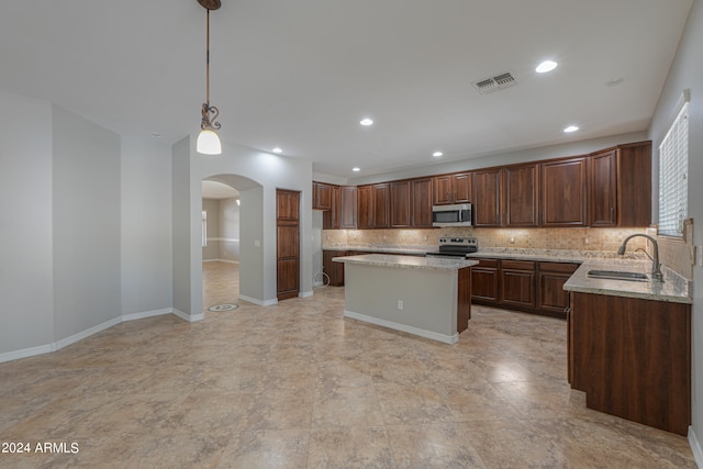 kitchen with hanging light fixtures, sink, tasteful backsplash, a kitchen island, and stainless steel appliances