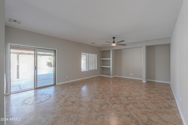 unfurnished room with built in shelves and ceiling fan