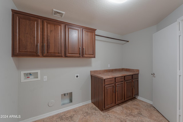 clothes washing area with hookup for an electric dryer, gas dryer hookup, a textured ceiling, cabinets, and hookup for a washing machine