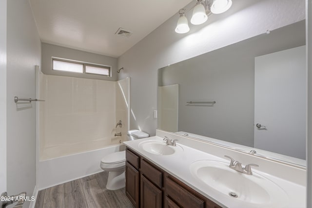 full bathroom with hardwood / wood-style flooring, vanity, washtub / shower combination, and toilet