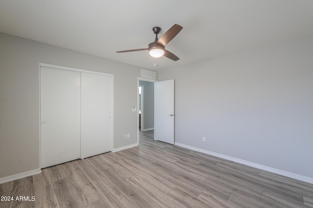 unfurnished bedroom featuring ceiling fan, a closet, and light hardwood / wood-style flooring