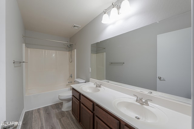 full bathroom featuring hardwood / wood-style floors, vanity, washtub / shower combination, and toilet