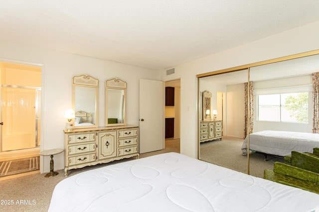 carpeted bedroom with visible vents, a textured ceiling, a closet, and connected bathroom