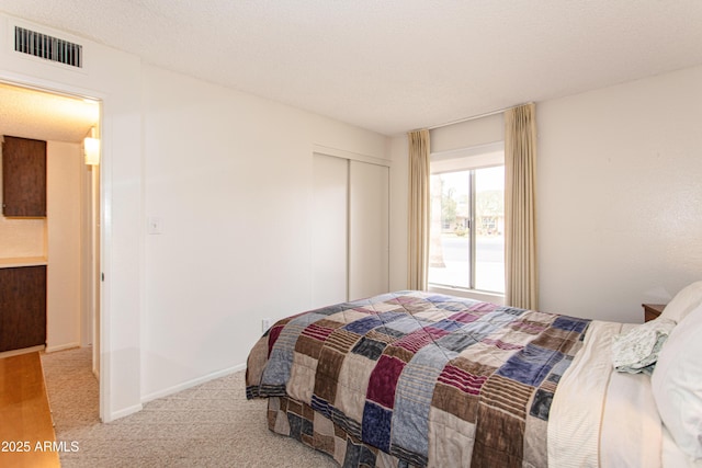 bedroom with visible vents, baseboards, carpet, a closet, and a textured ceiling