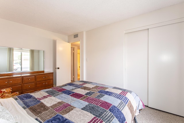 bedroom with a textured ceiling, visible vents, a closet, and light carpet