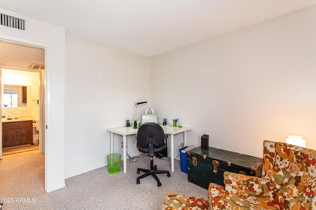 carpeted office featuring visible vents and a textured ceiling