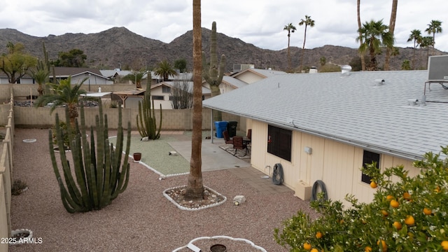 exterior space featuring a mountain view, a shingled roof, and a fenced backyard