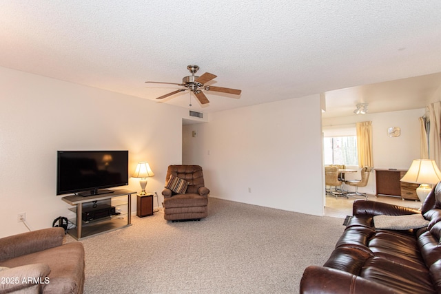 living area with carpet flooring, a ceiling fan, visible vents, and a textured ceiling