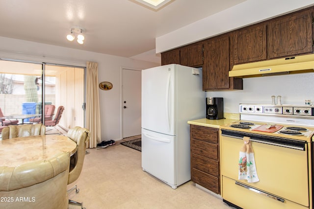 kitchen featuring under cabinet range hood, dark brown cabinetry, light floors, light countertops, and white appliances