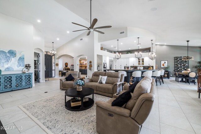 living room featuring ceiling fan with notable chandelier, high vaulted ceiling, and light tile patterned flooring