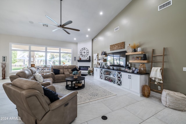 living room featuring high vaulted ceiling, light tile patterned floors, ceiling fan, and a large fireplace