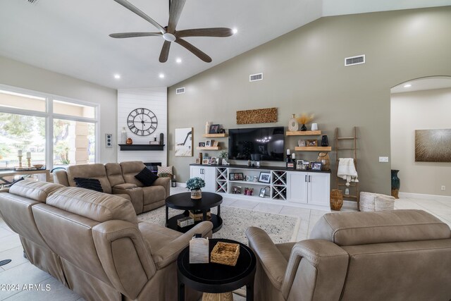 tiled living room featuring a fireplace, high vaulted ceiling, and ceiling fan