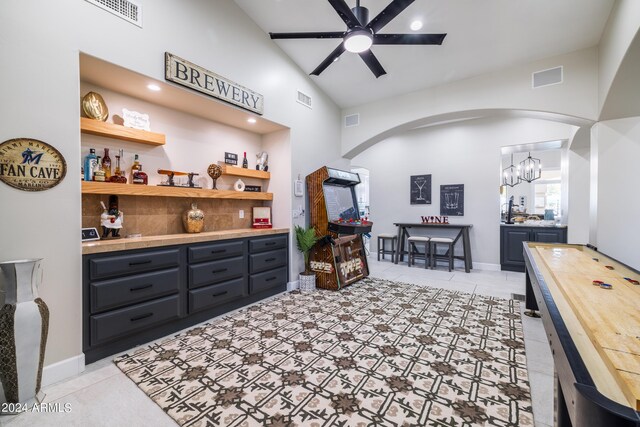 sitting room with light tile patterned floors, ceiling fan with notable chandelier, and high vaulted ceiling