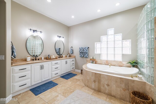 bathroom with tile patterned flooring, tiled tub, and vanity