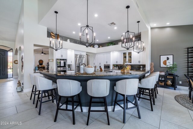 kitchen with hanging light fixtures, stainless steel appliances, ceiling fan with notable chandelier, and white cabinetry