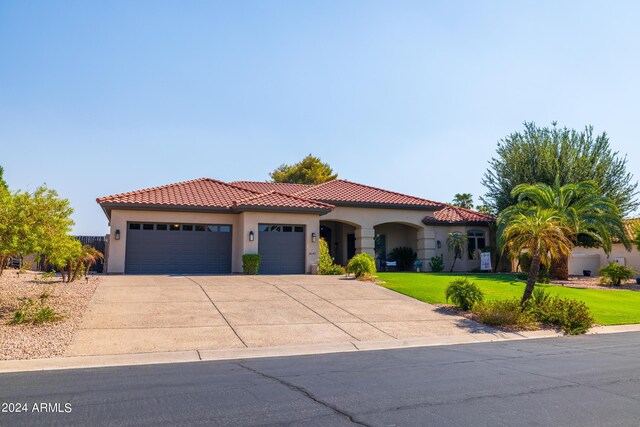 mediterranean / spanish house with a front yard and a garage