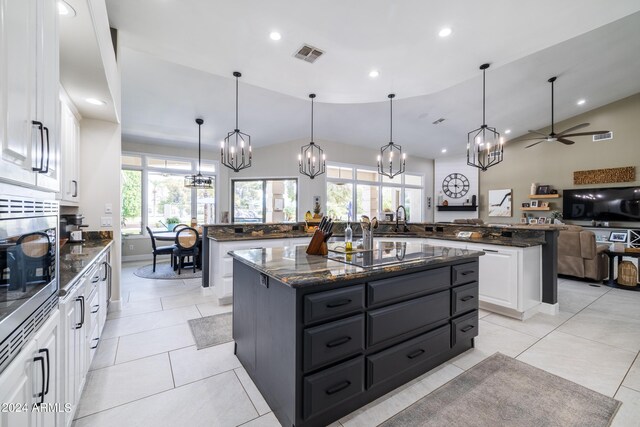 kitchen with a kitchen island, vaulted ceiling, ceiling fan with notable chandelier, and white cabinets