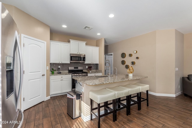 kitchen featuring a breakfast bar, white cabinetry, dark wood-type flooring, sink, and stainless steel appliances