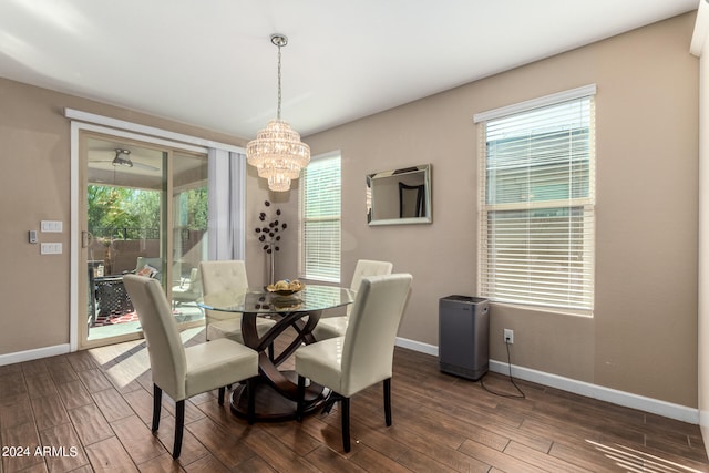 dining area with dark hardwood / wood-style floors, ceiling fan with notable chandelier, and a wealth of natural light