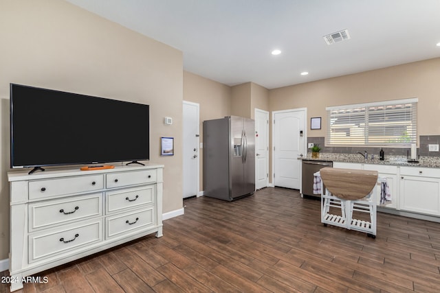 kitchen featuring dark wood-type flooring, white cabinetry, light stone counters, and stainless steel appliances