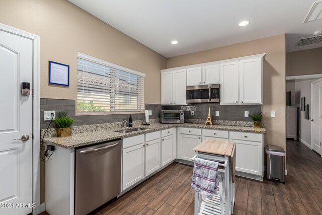 kitchen with tasteful backsplash, white cabinetry, stainless steel appliances, light stone counters, and dark hardwood / wood-style floors