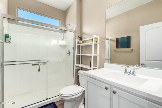 bathroom with a shower with door, vanity, wood-type flooring, and toilet