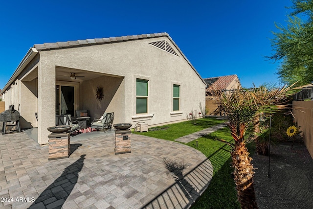 rear view of house with a patio area, a yard, and ceiling fan