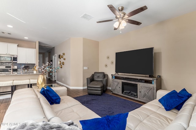 living room with dark wood-type flooring and ceiling fan