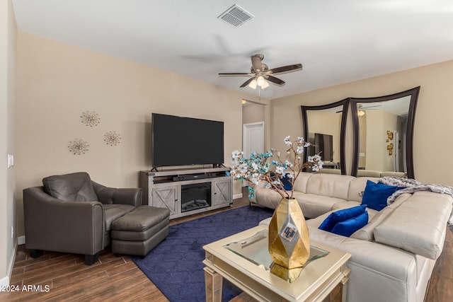 living room with dark wood-type flooring, ceiling fan, and a fireplace