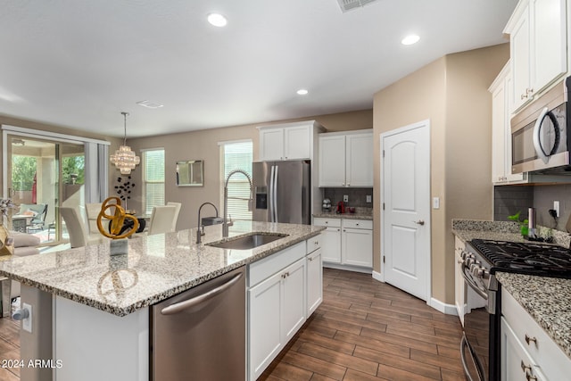 kitchen with dark wood-type flooring, appliances with stainless steel finishes, a kitchen island with sink, and white cabinetry