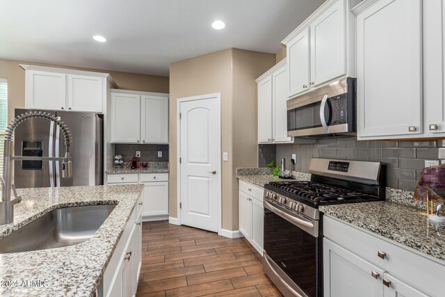 kitchen with appliances with stainless steel finishes, white cabinetry, backsplash, and dark hardwood / wood-style floors