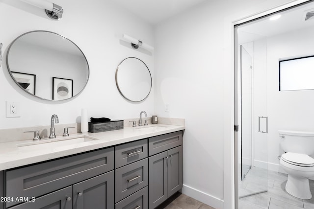 full bathroom with a shower stall, double vanity, a sink, and toilet
